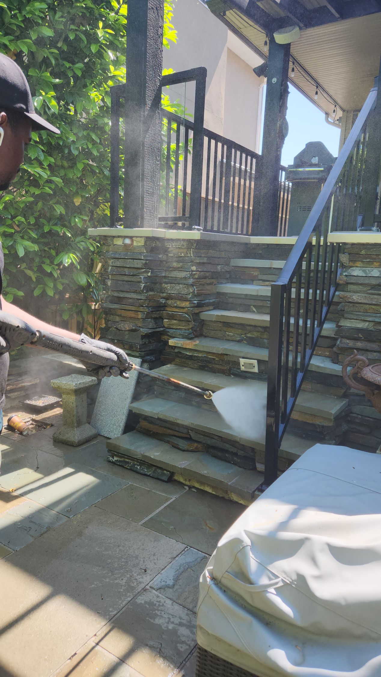 A man is using a pressure washer to clean a stone staircase.