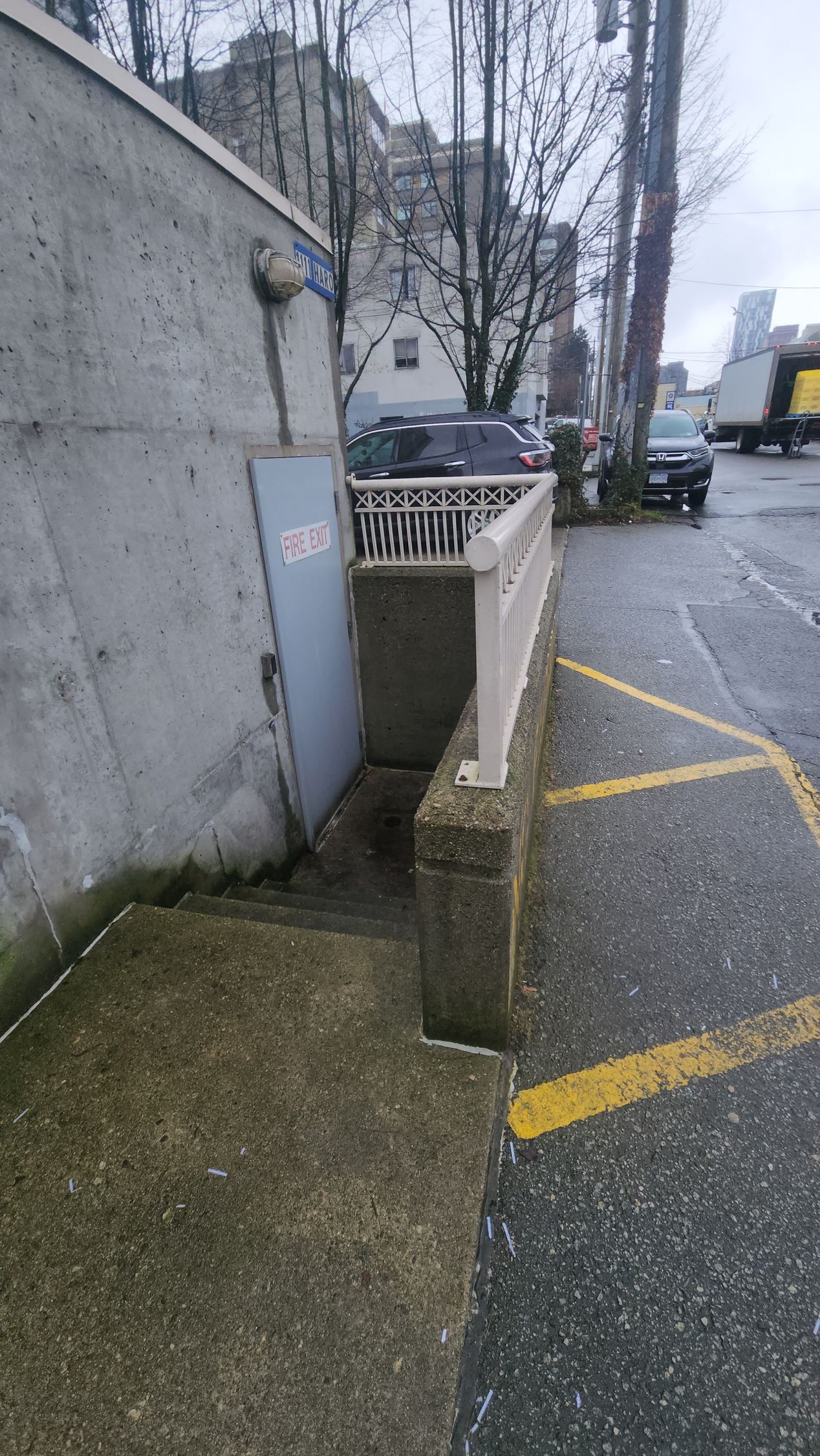 A concrete wall with stairs leading up to it and a yellow line on the sidewalk.