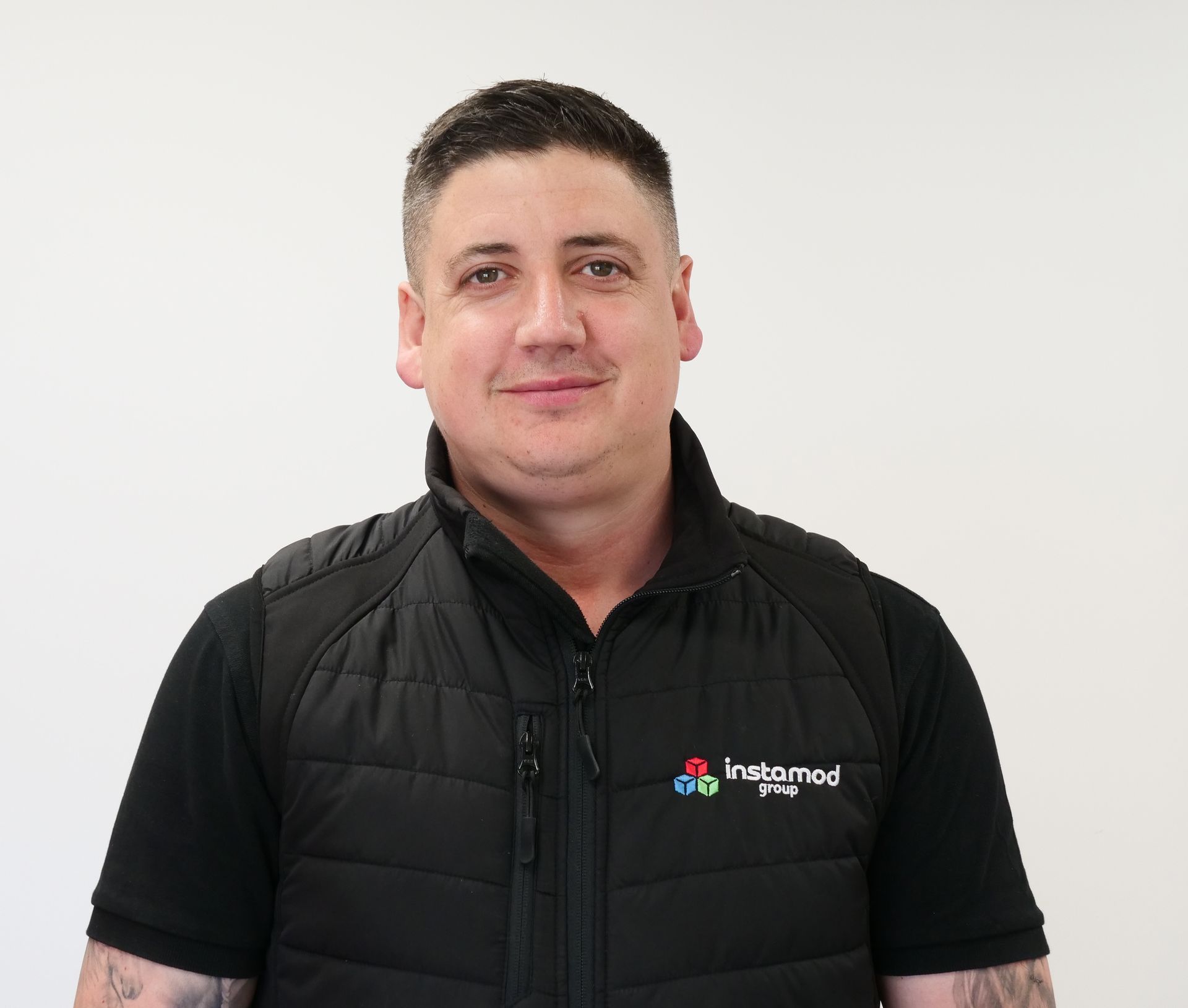A man wearing a black vest and a black shirt is smiling for the camera.