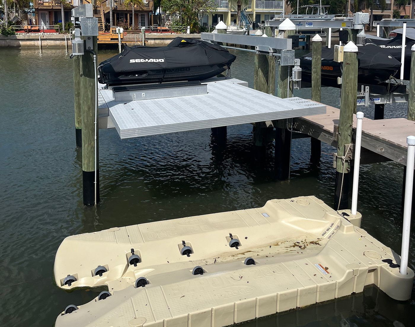 Two small boats moored at a marina dock on calm water under a partly cloudy sky