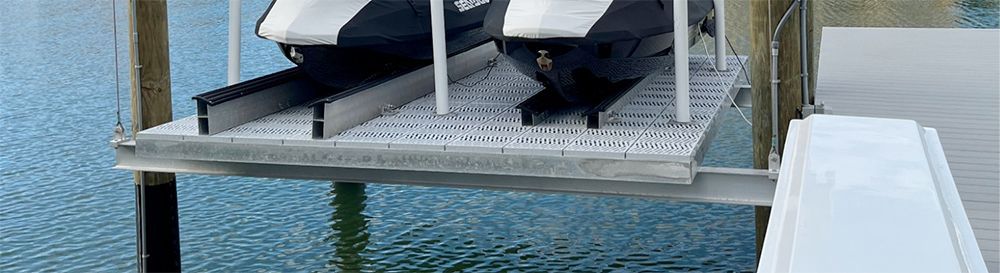 Jet skis on a lift over water. Gray and white colors.