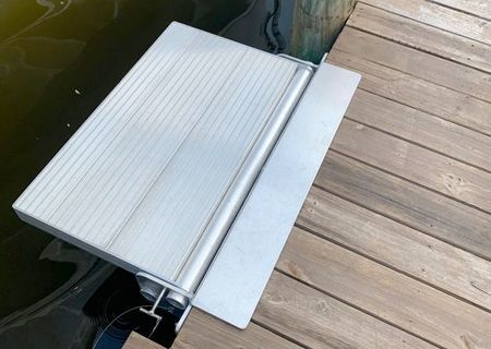 Aluminum ramp extending from a wooden dock into the water.