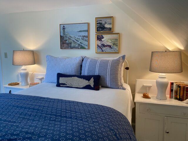 Cozy bedroom with blue bedding, bedside lamps, and framed wall art