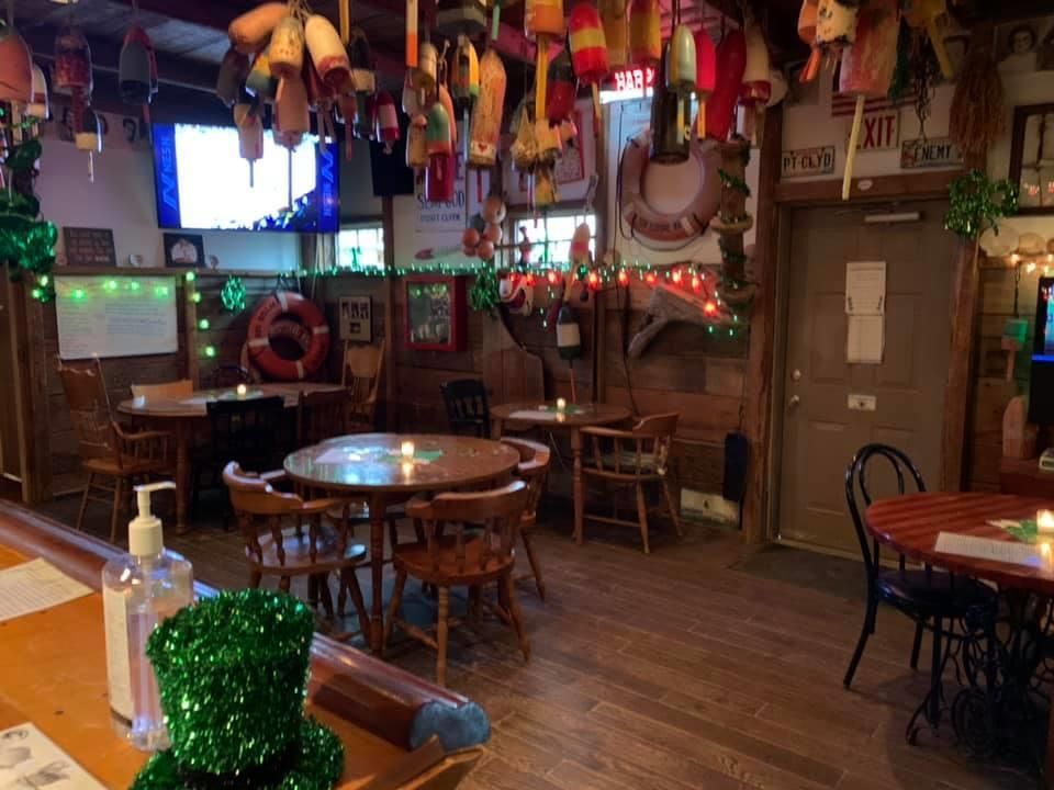 Cozy bar interior with wooden tables, stools, string lights, and festive wall decor