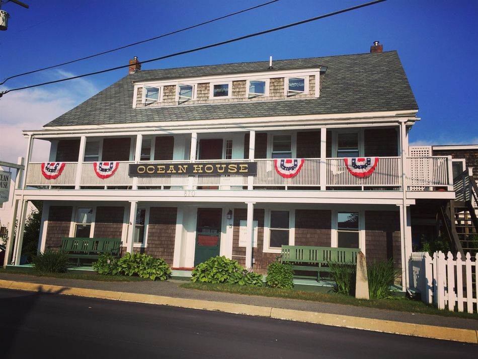 Historic two-story white house with red bunting and a porch under a blue sky