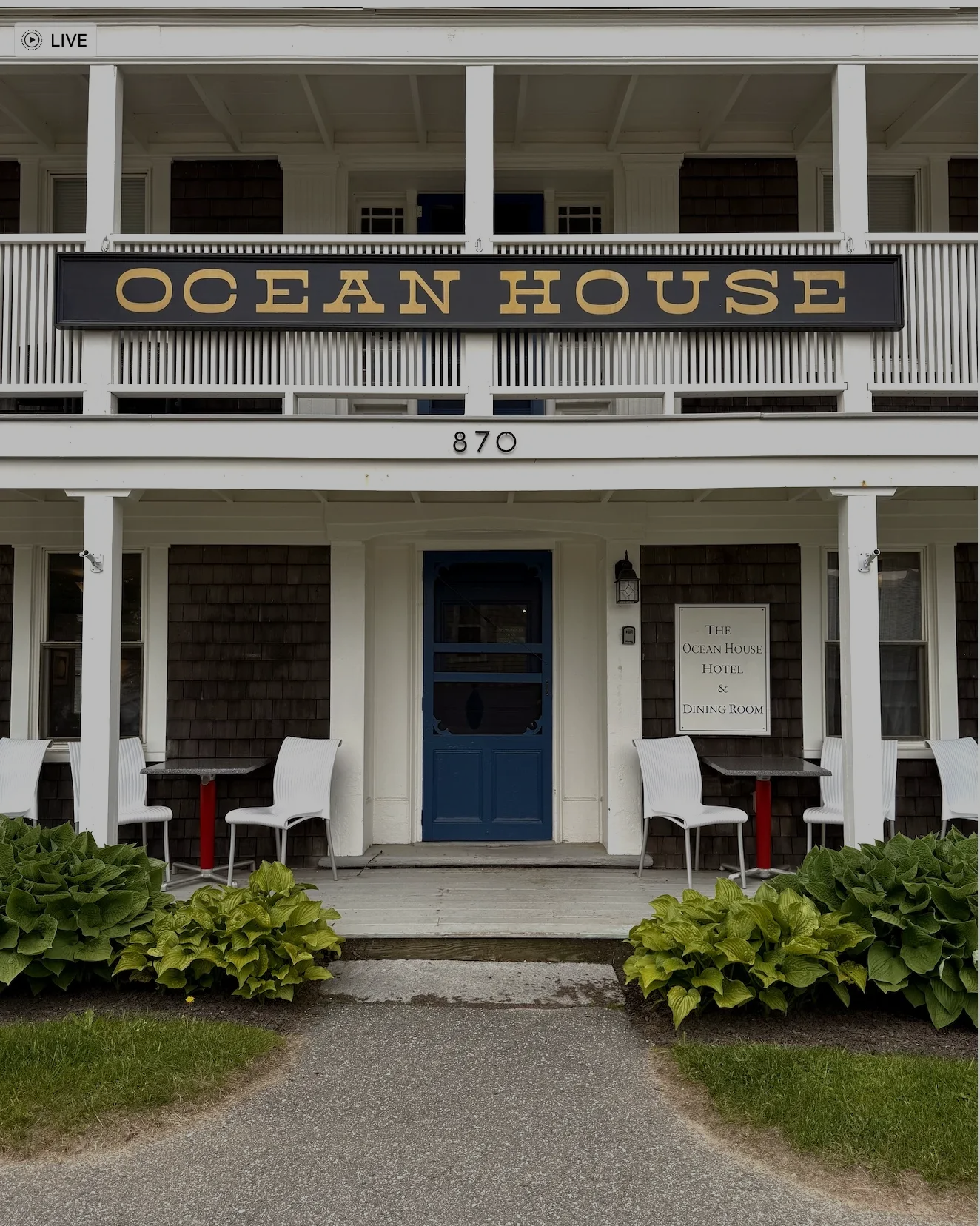 Ocean House storefront with blue door, white porch, and hanging sign above the entrance.