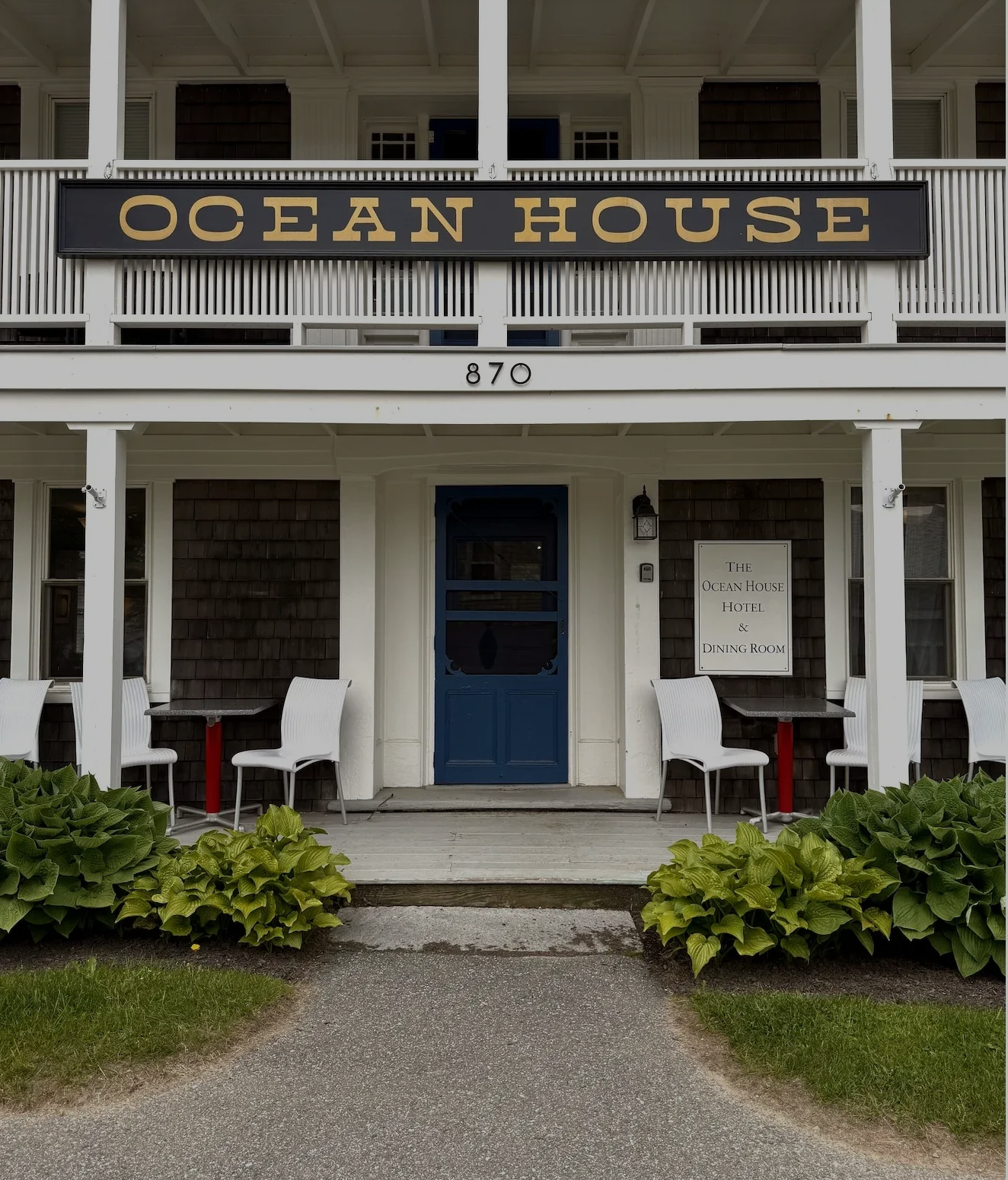 Ocean House storefront with blue door, white porch columns, and outdoor seating