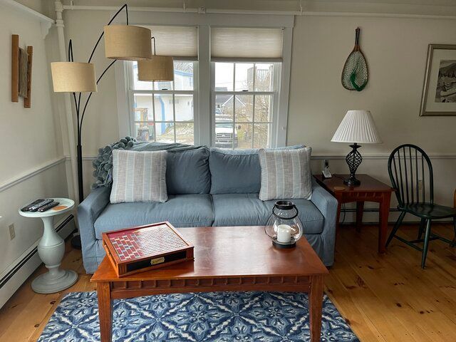 Cozy living room with blue sofa, wooden coffee table, floor lamps, and chair by the window.
