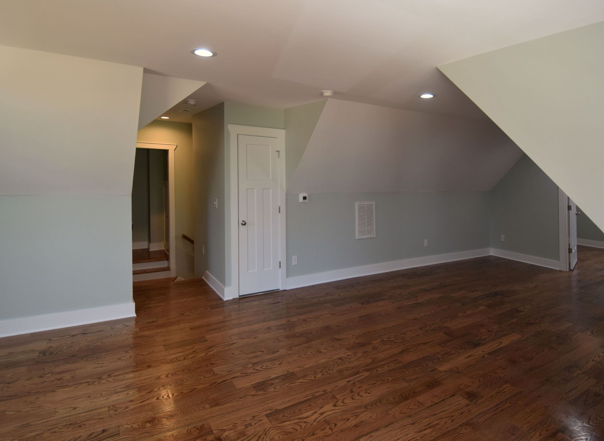 An empty room with hardwood floors and white walls.