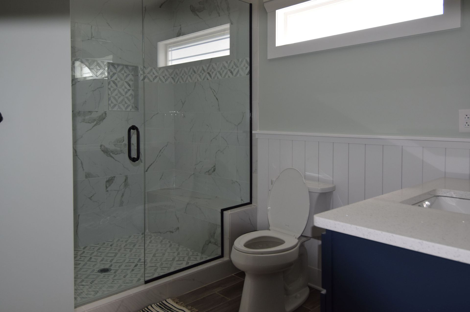 A bathroom with a toilet , sink , shower and window.
