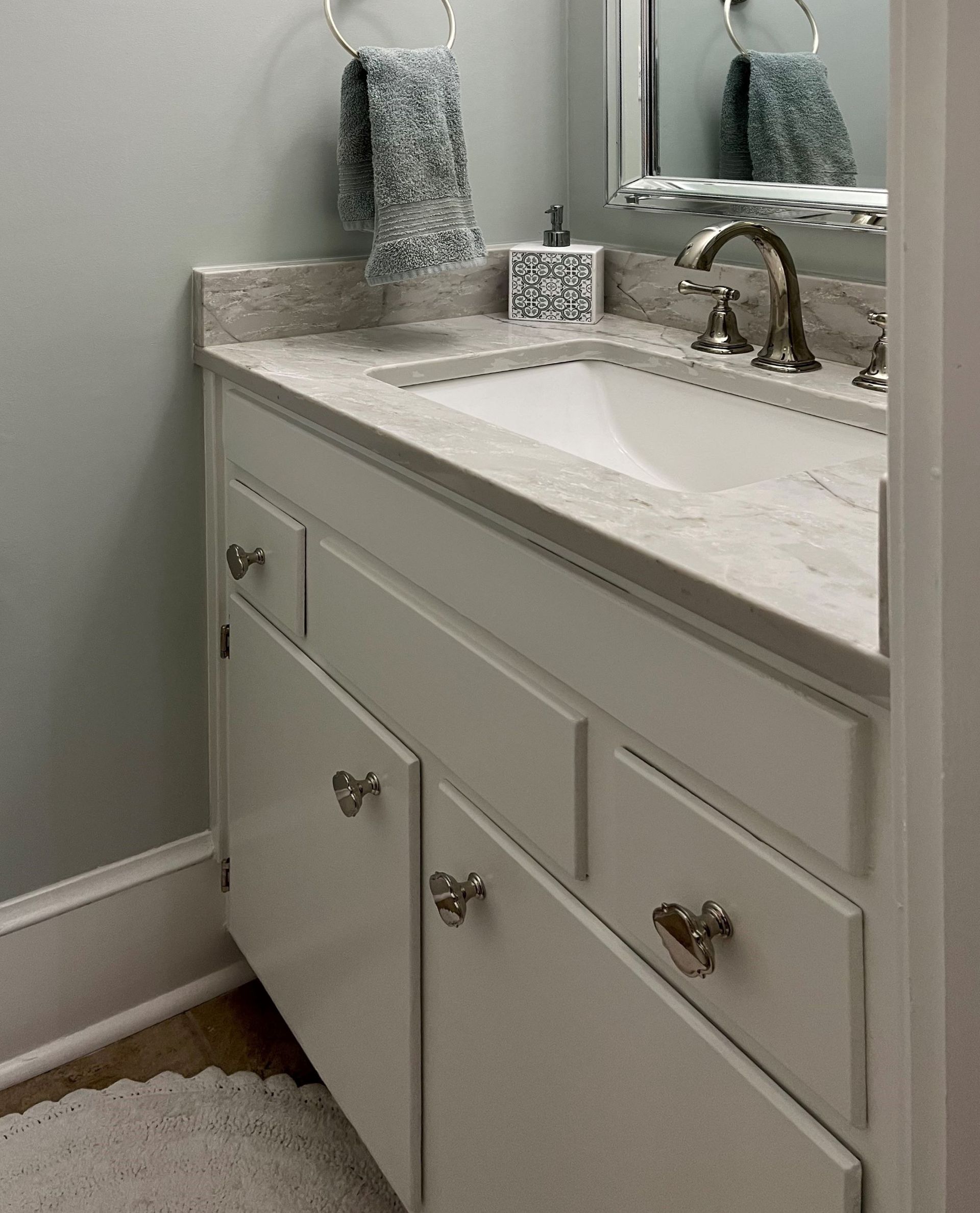 White bathroom vanity with marble countertop and a sink.