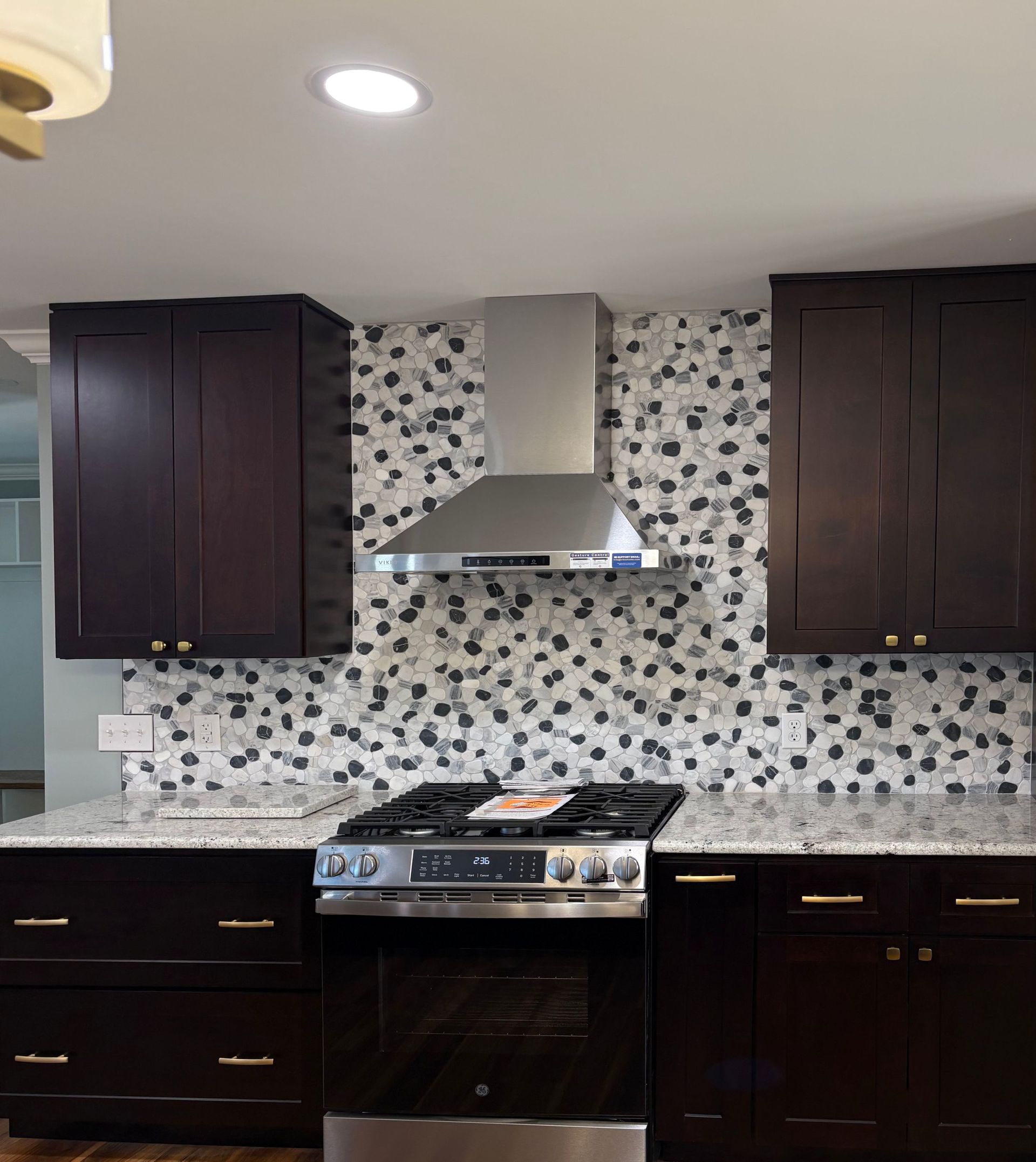 Kitchen with dark cabinets, stainless steel appliances, and mosaic tile backsplash.
