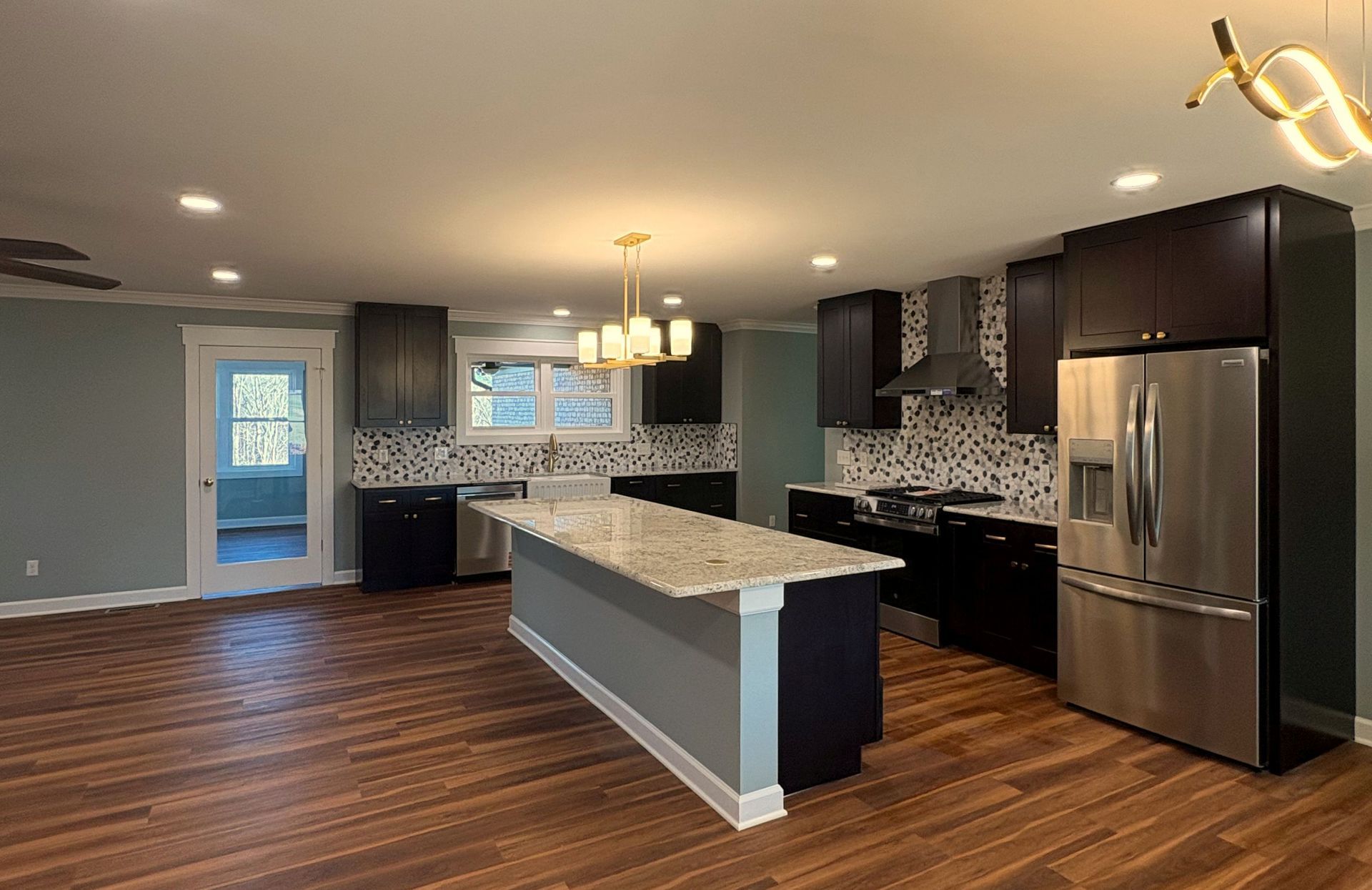 Modern kitchen with dark cabinets, stainless steel appliances, and a central island.