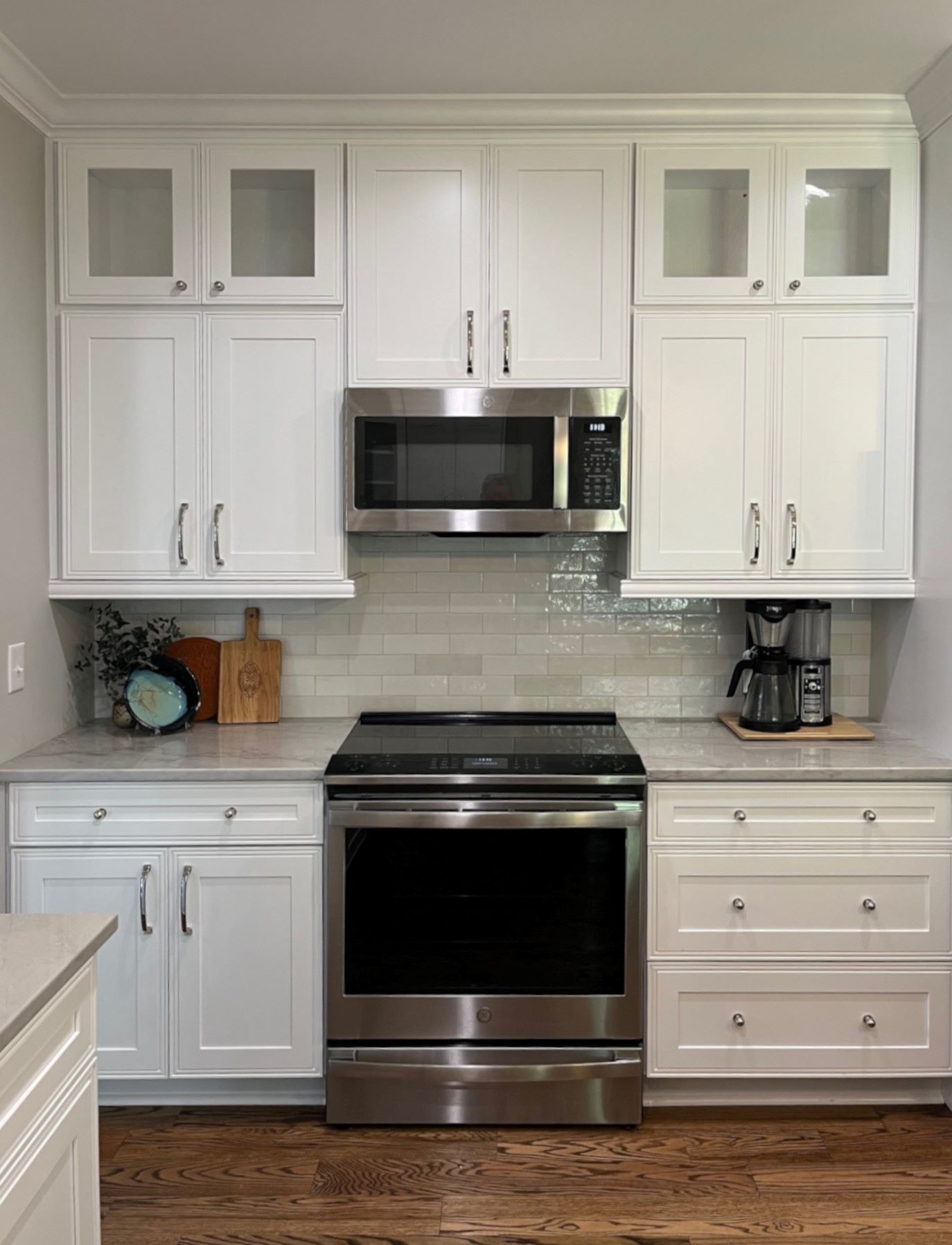 White kitchen with stainless steel appliances, cabinets, and light gray backsplash.