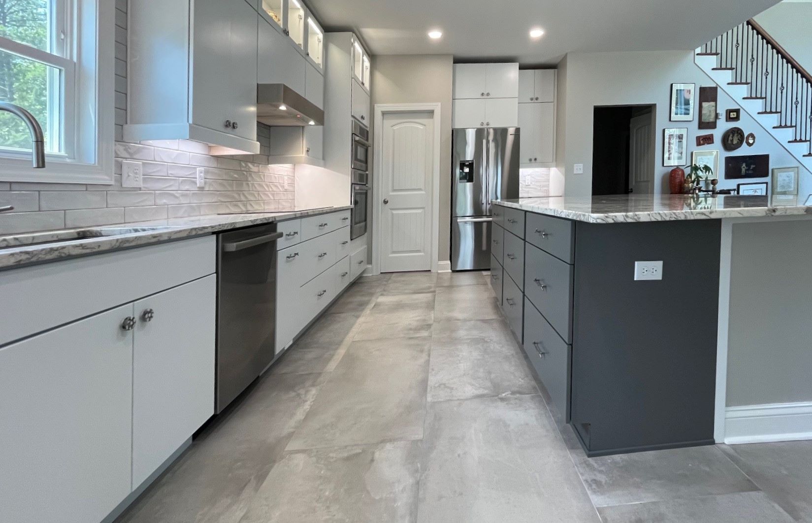 Modern kitchen with gray and white cabinets, stainless steel appliances, and a gray island.