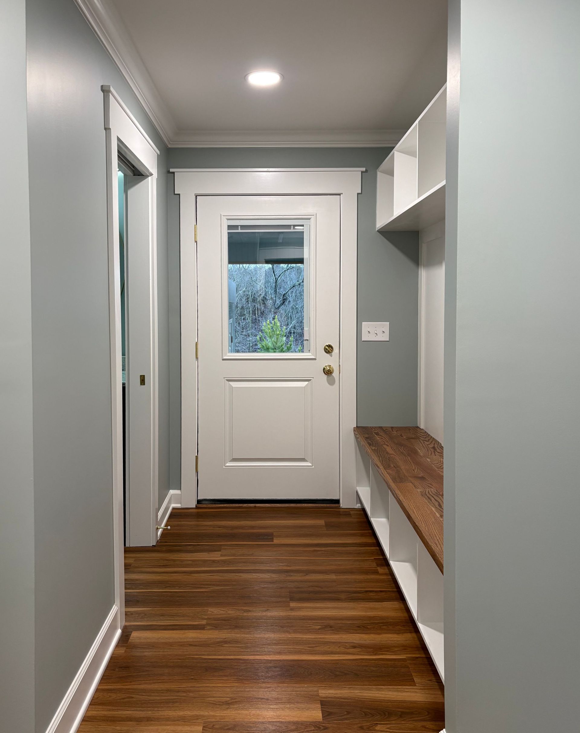 Hallway with a door, built-in bench, white trim, and light blue walls.