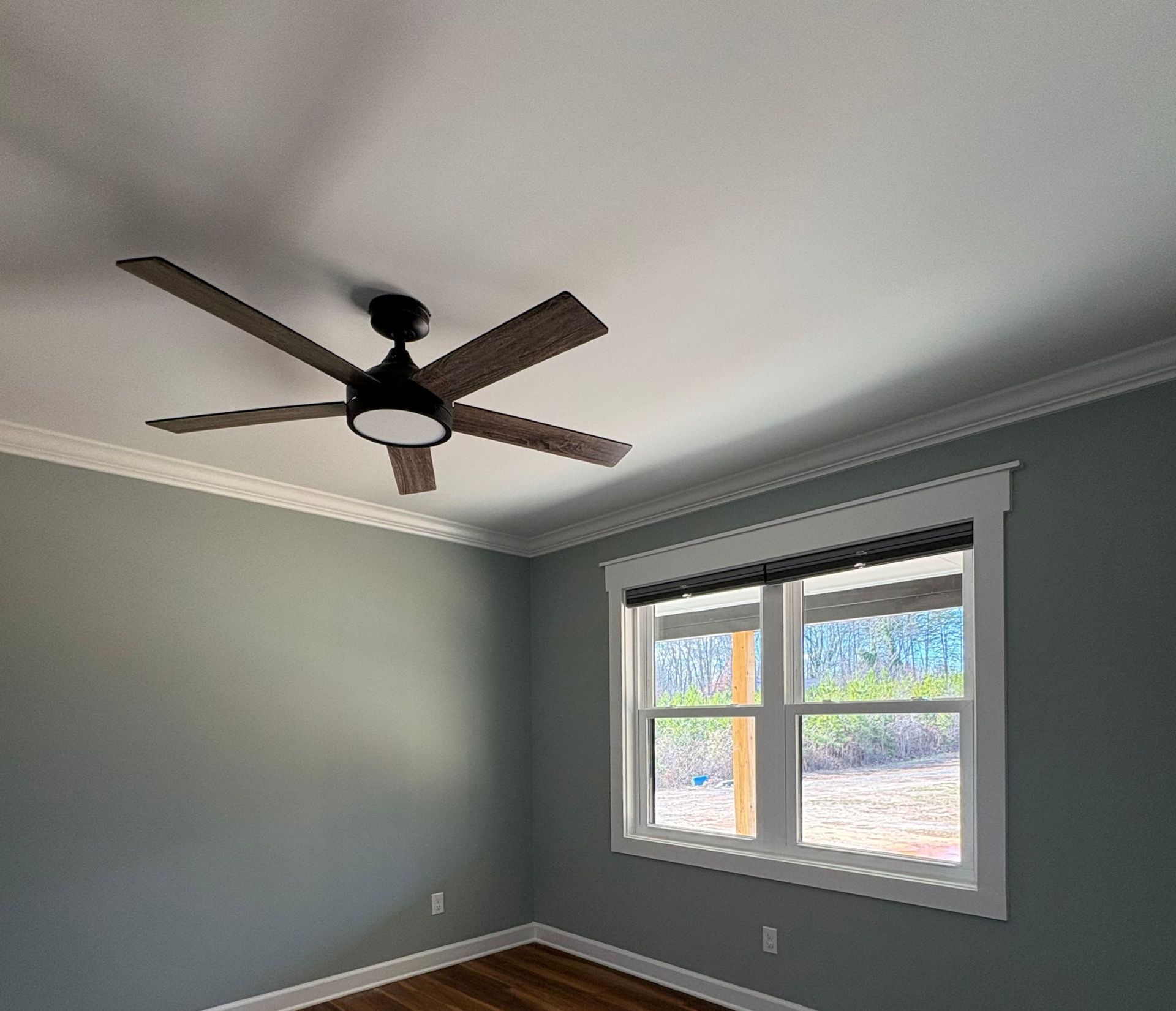 A bedroom with teal walls, crown molding, a ceiling fan, and a window with blinds.