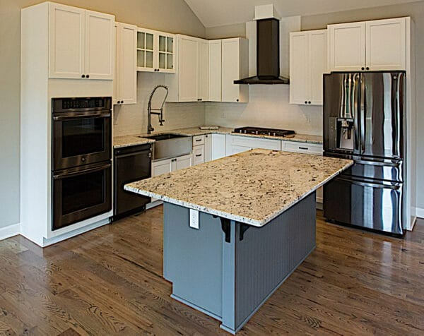 A kitchen with white cabinets , granite counter tops , stainless steel appliances and a large island.