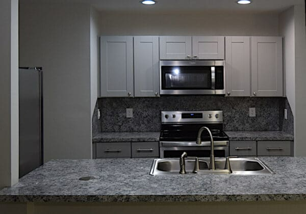 A kitchen with a sink , stove , microwave and refrigerator.