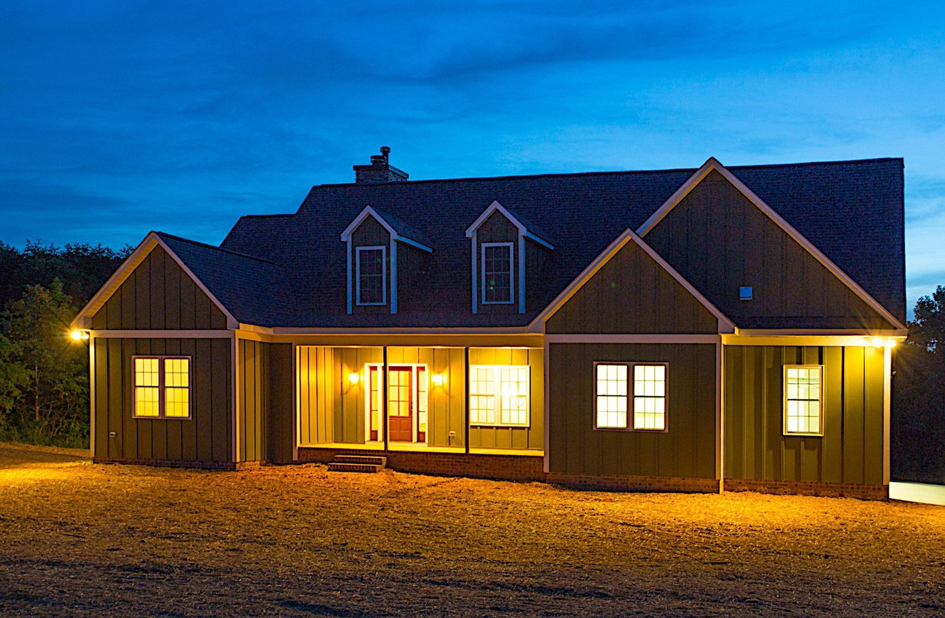 A house is lit up at night with a blue sky in the background.
