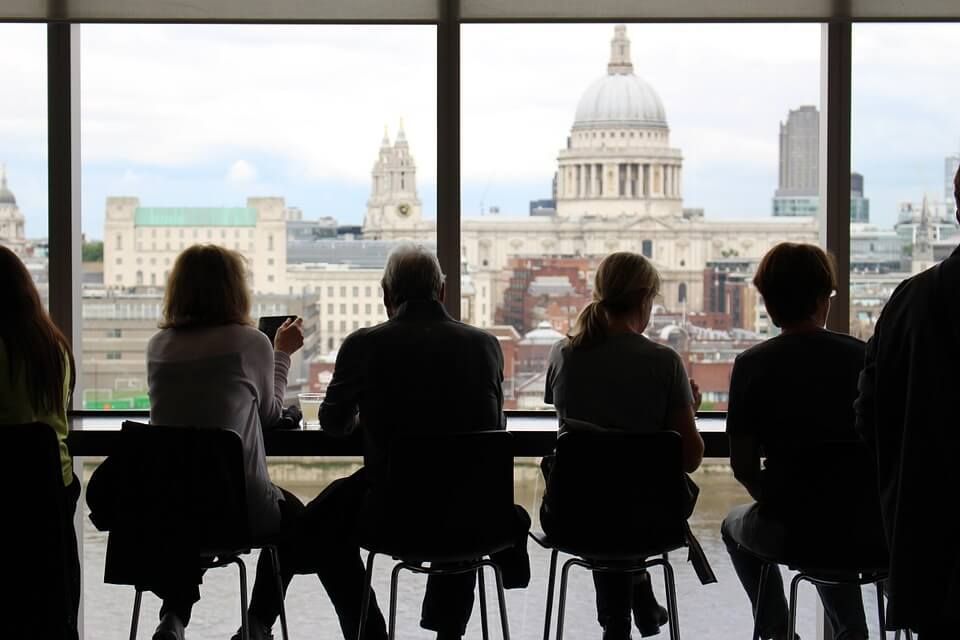 A group of people are sitting in front of a window looking out at a city.