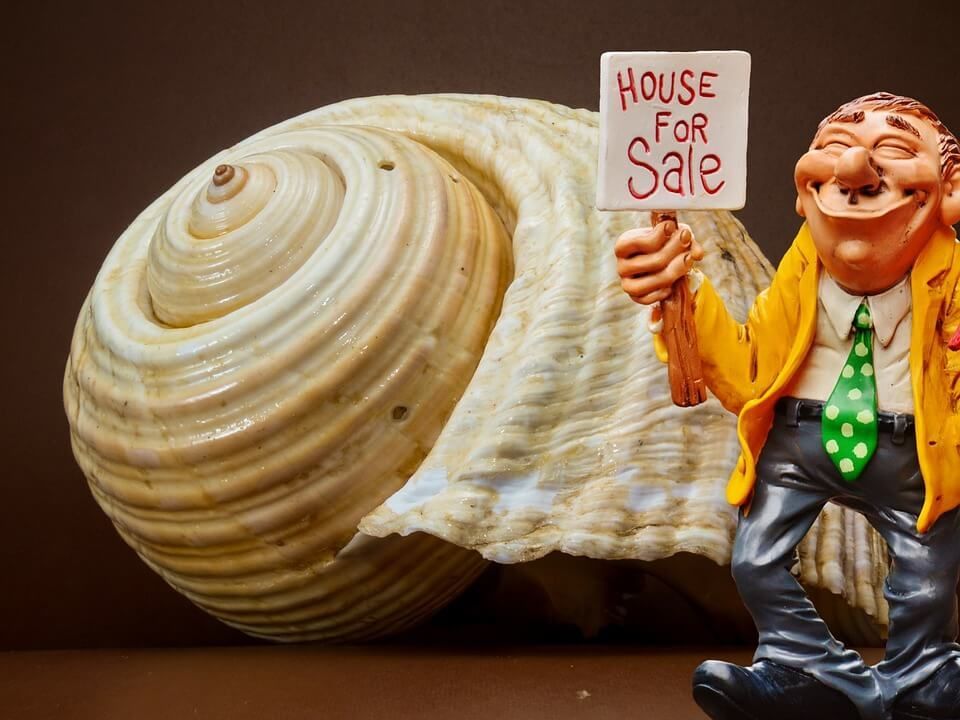 A figurine of a man holding a sign that says house for sale