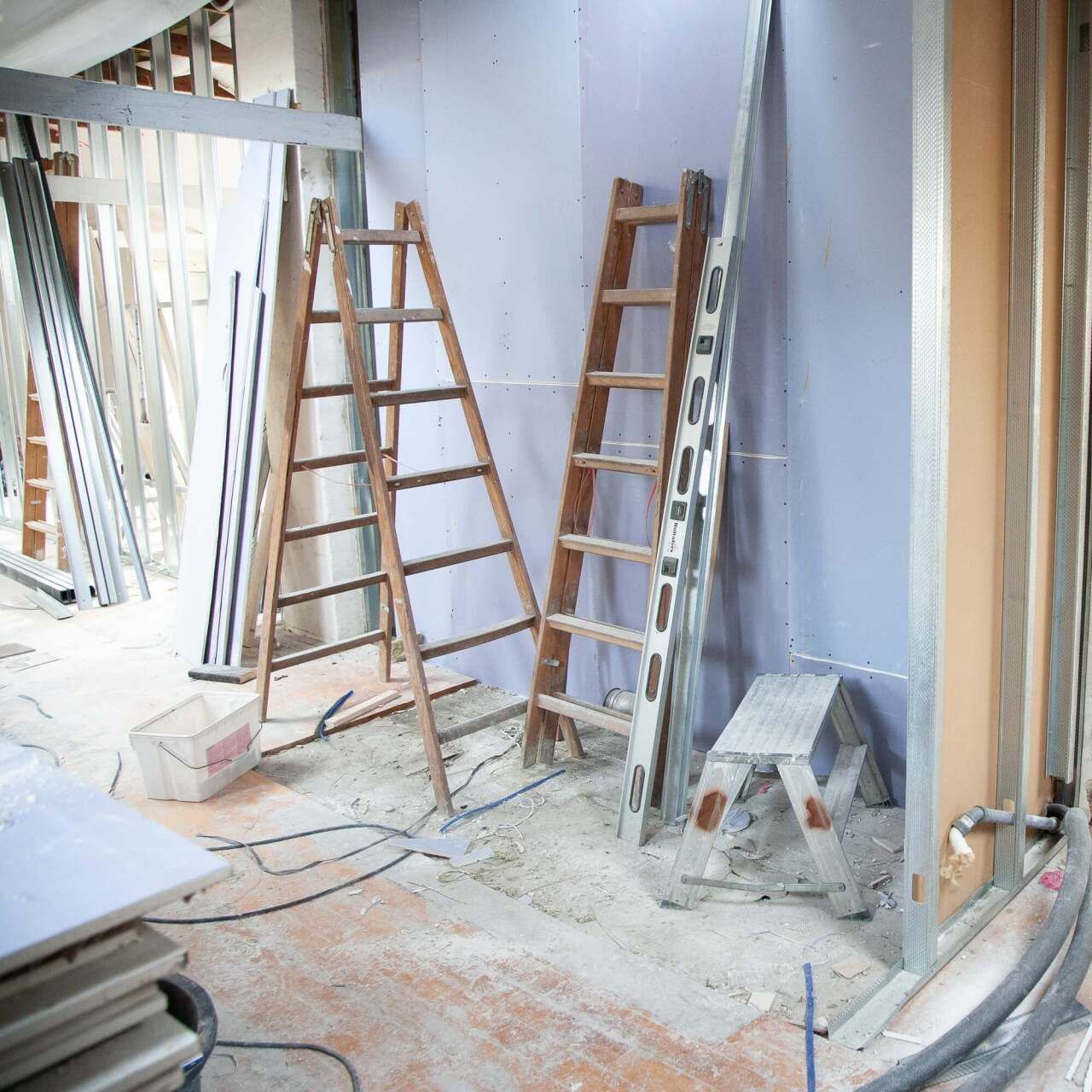 A room under construction with ladders and a stool