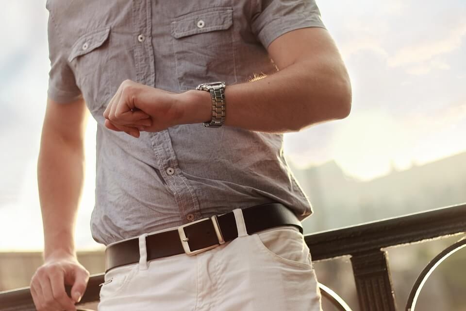 A man wearing a watch is looking at his watch.