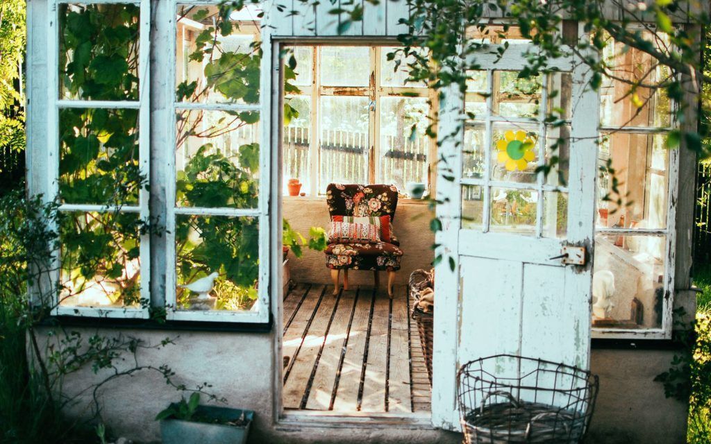A greenhouse with a chair and a basket in front of it.