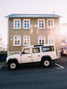 A white jeep is parked in front of a wooden building.