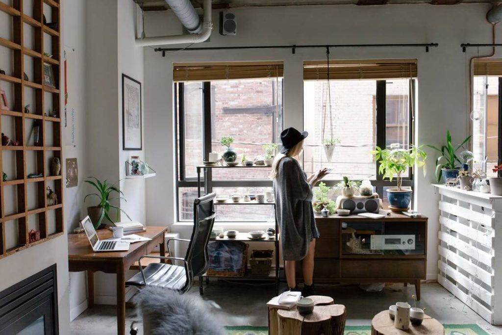 A woman is standing in a living room looking out a window.