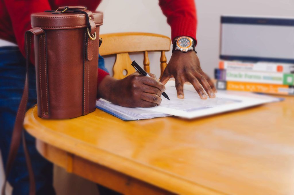 A person is sitting at a table writing on a piece of paper.