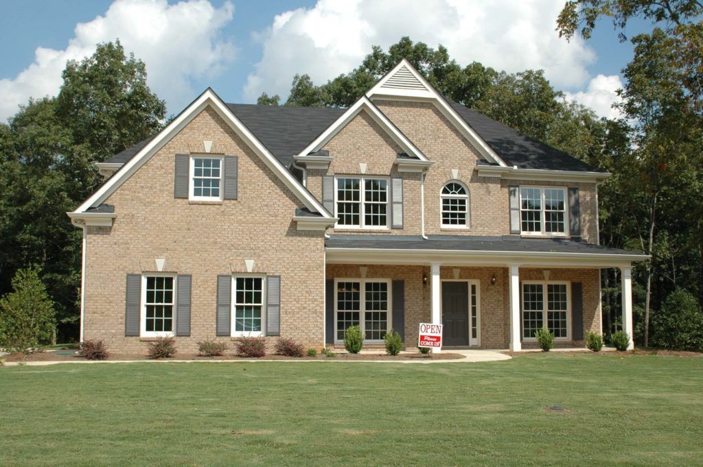 A large brick house with a for sale sign in front of it
