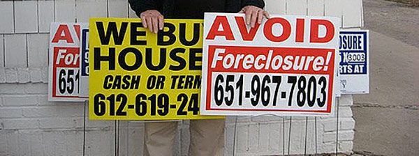 A man is holding a sign that says we buy house foreclosure