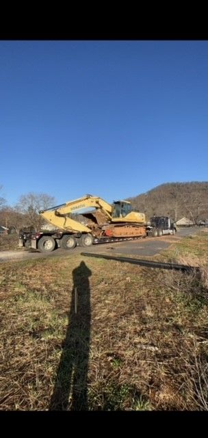 A Large Excavator is Driving Down a Dirt Road Next to a Truck | Weaverville, NC | Appalachian Trucking LLC