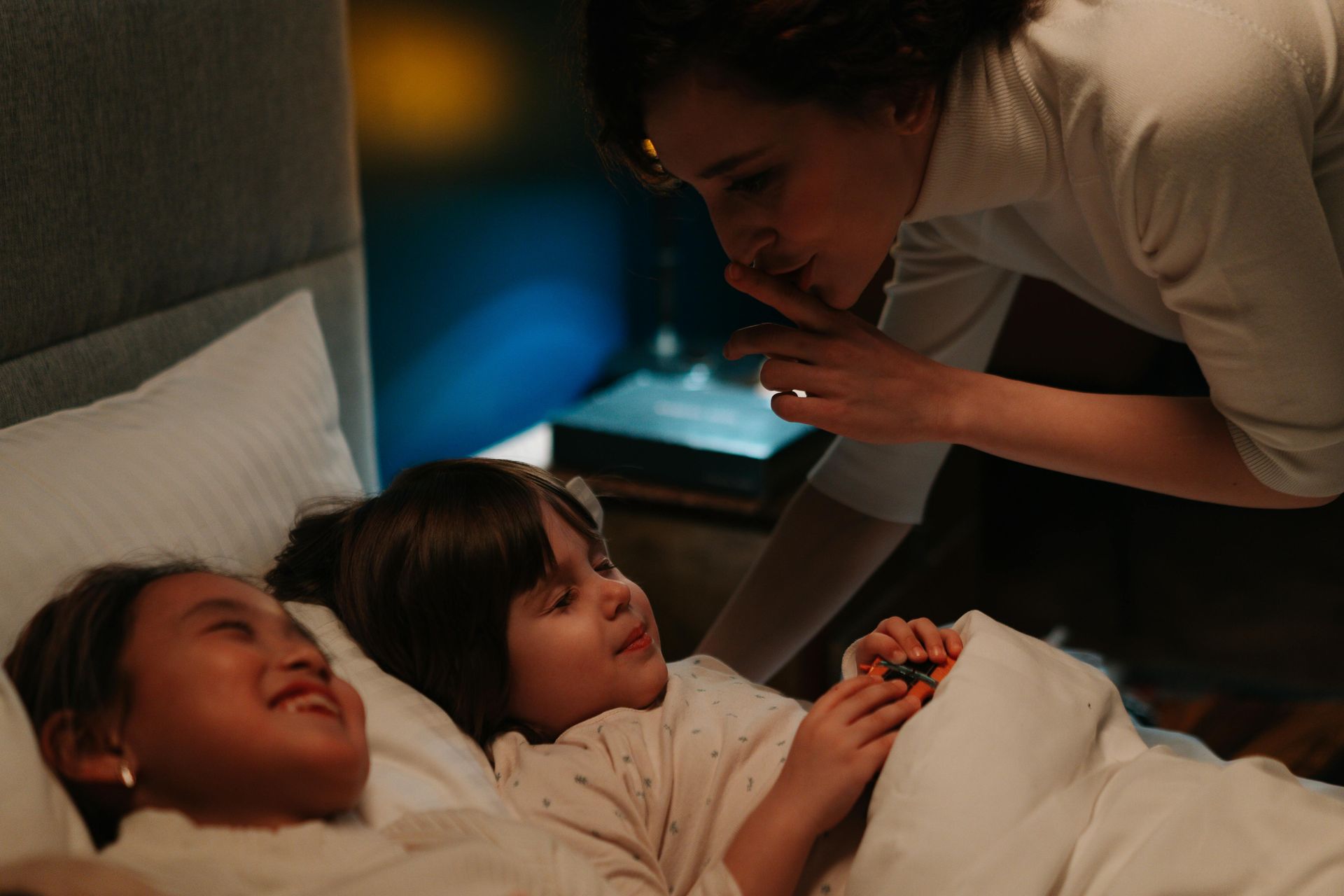 Mom tucks her children into bed