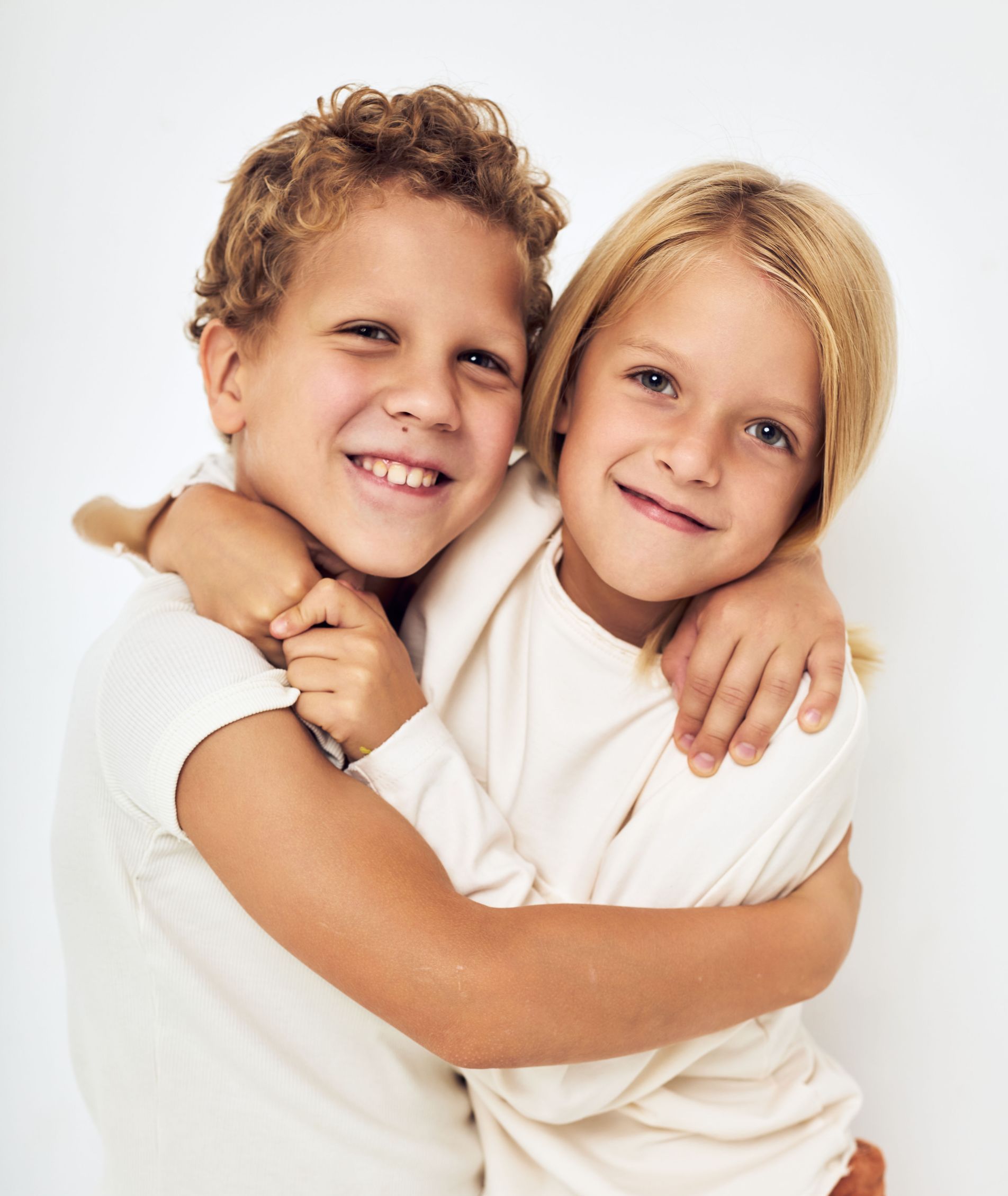 A boy and a girl are hugging each other and smiling