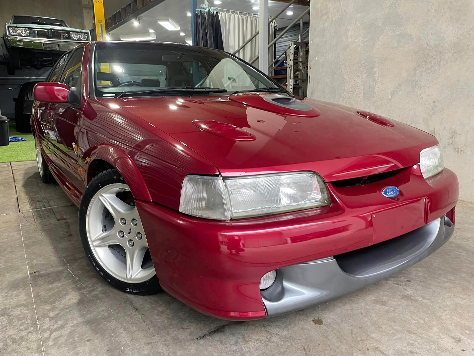 A red ford mustang is parked in a garage.
