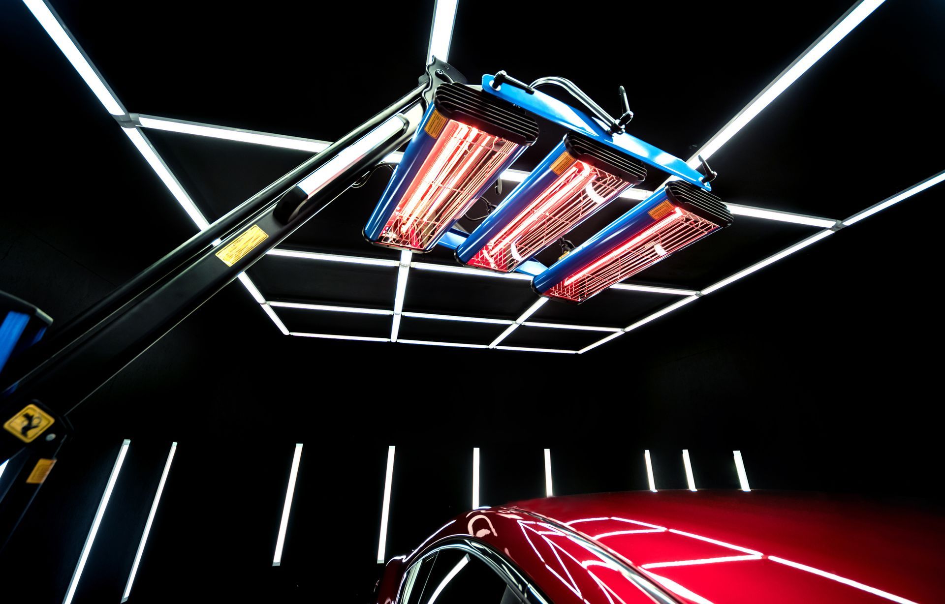 Infrared lamps overhead drying a car body after applying ceramic sealant.