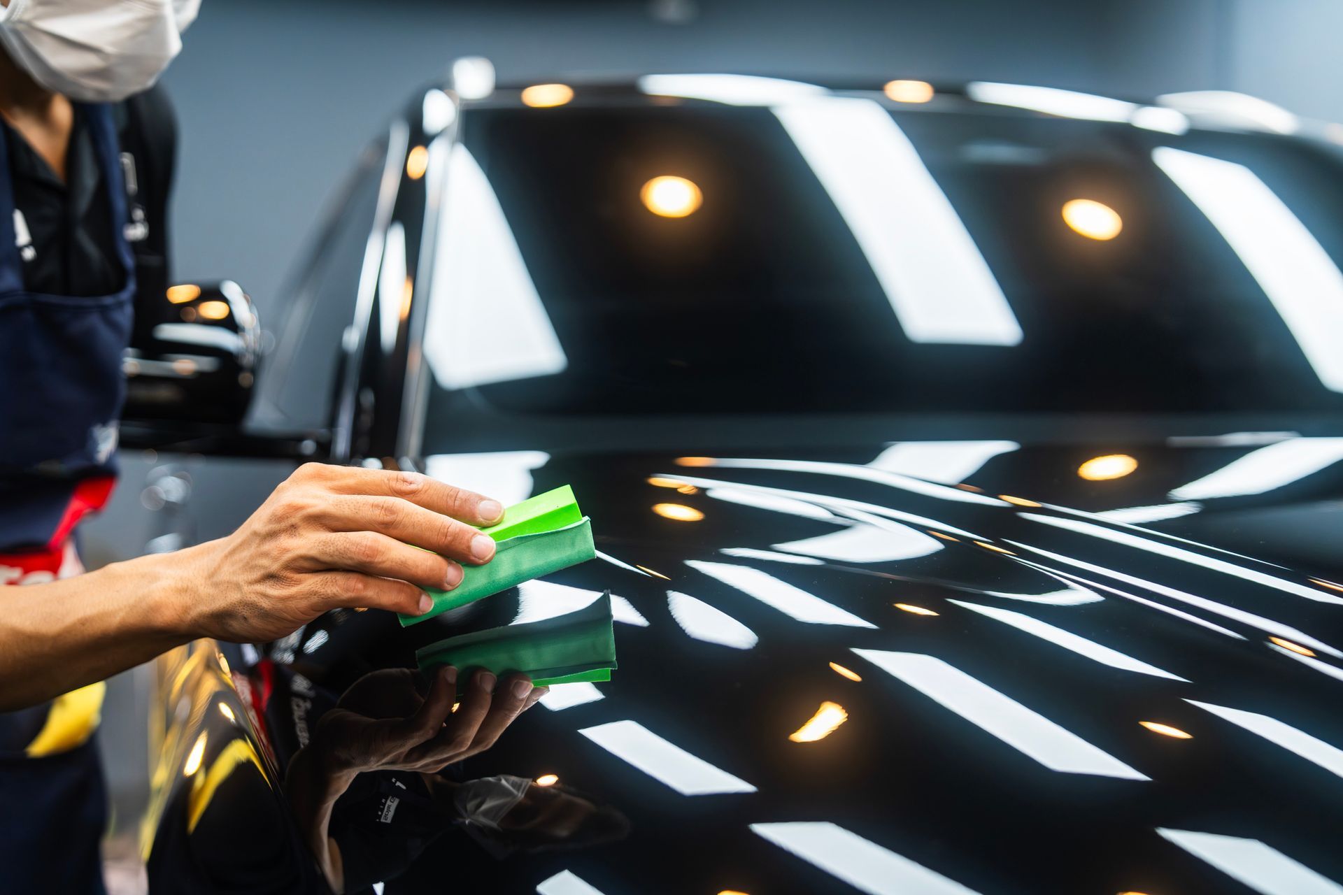 Professional polisher perfecting a car's exterior, enhancing its shine.