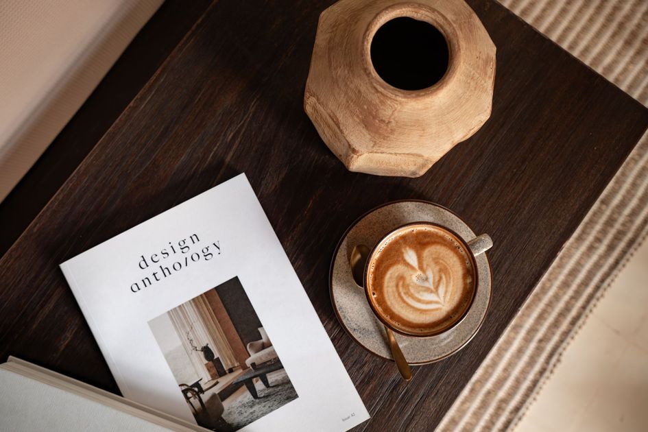 Top-down view of a coffee and magazine on a dark wooden tray with a vase.