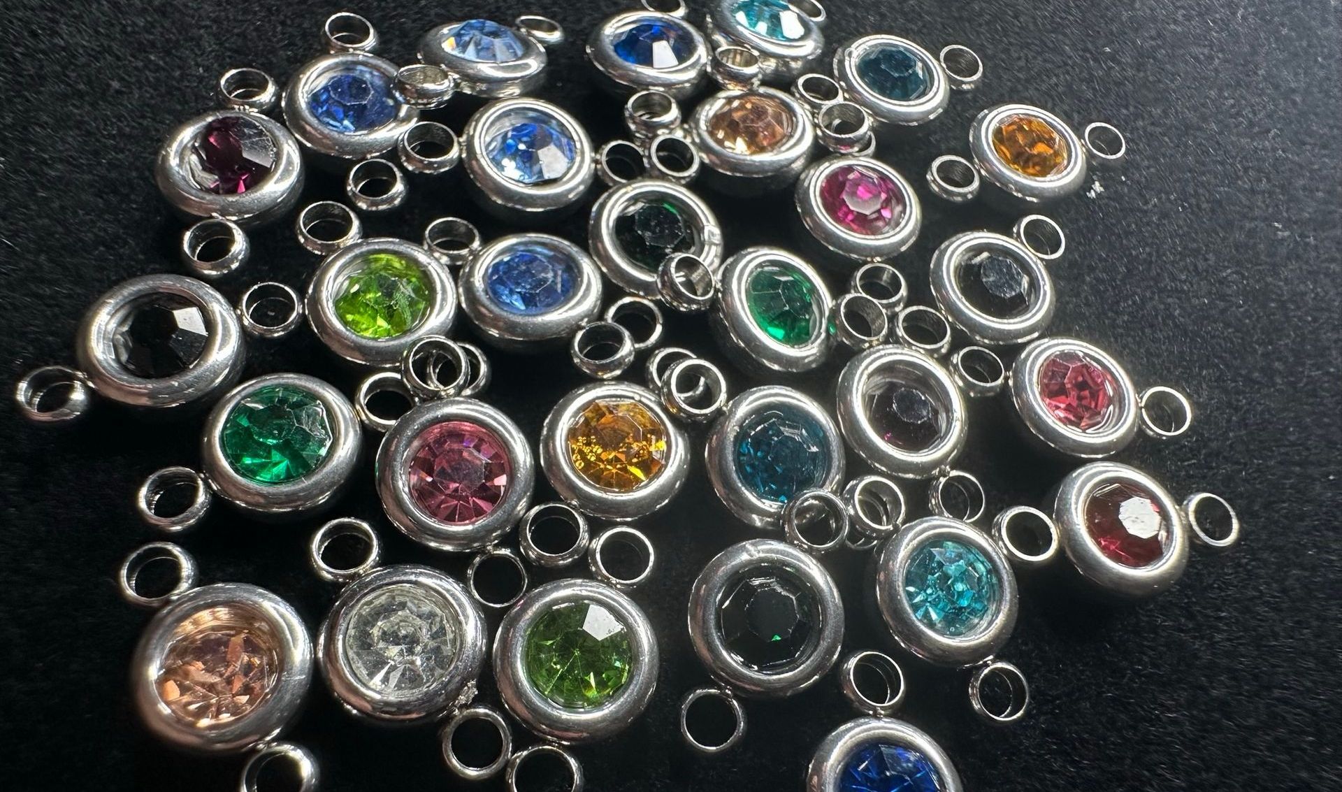 Assorted colorful gemstone pendants with silver settings and small connecting loops.