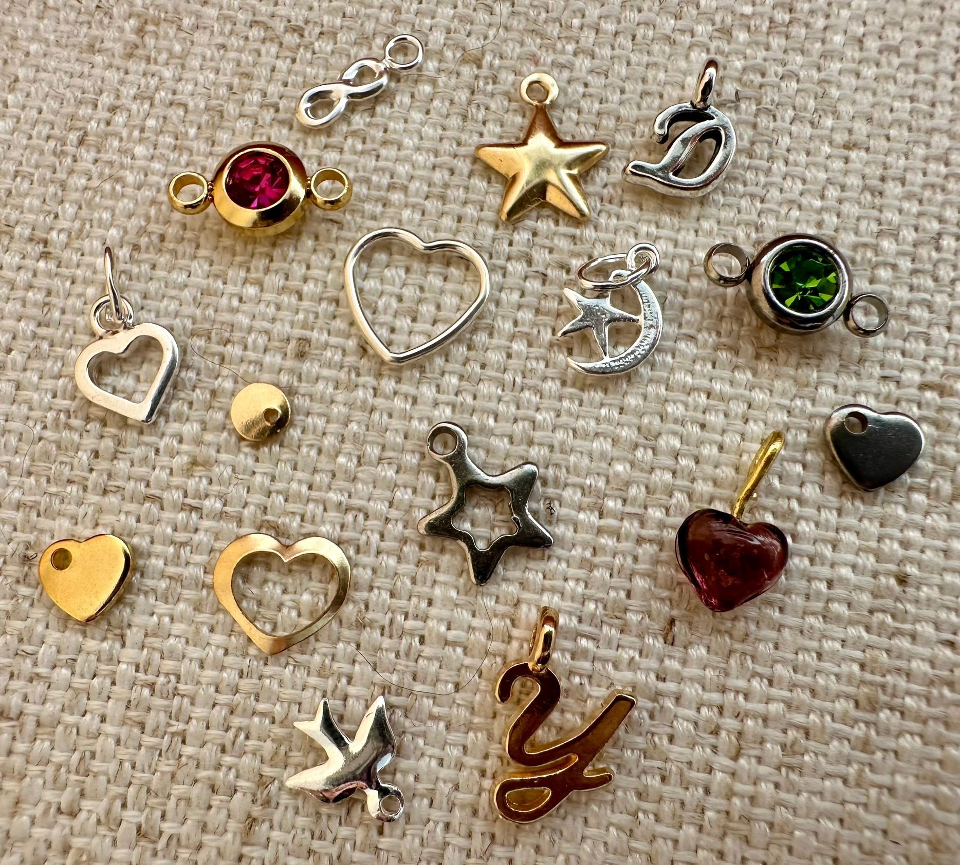 Collection of small metal charms in various shapes: hearts, stars, and abstract designs.