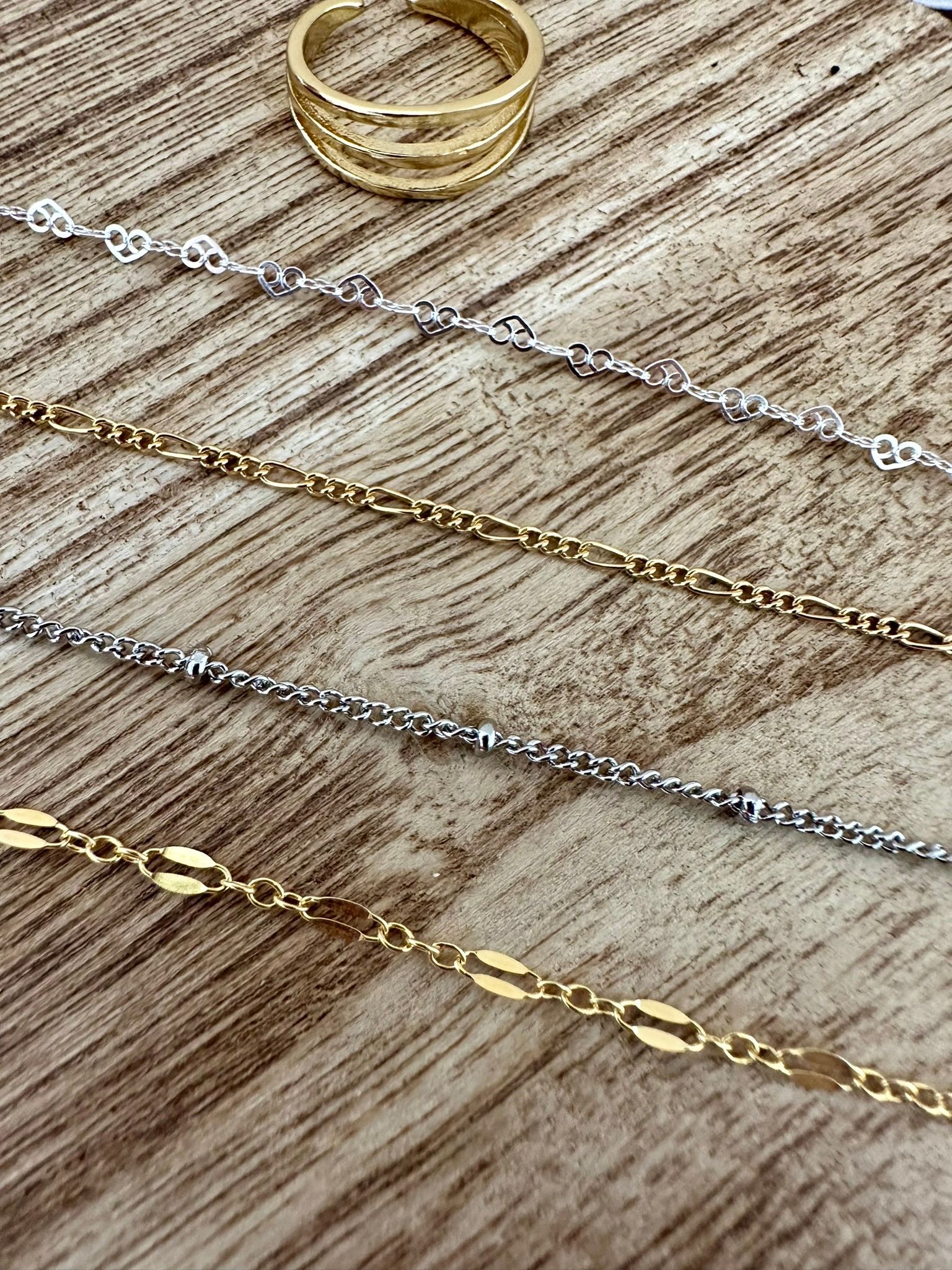 Gold ring and various gold and silver necklaces on a wooden surface.