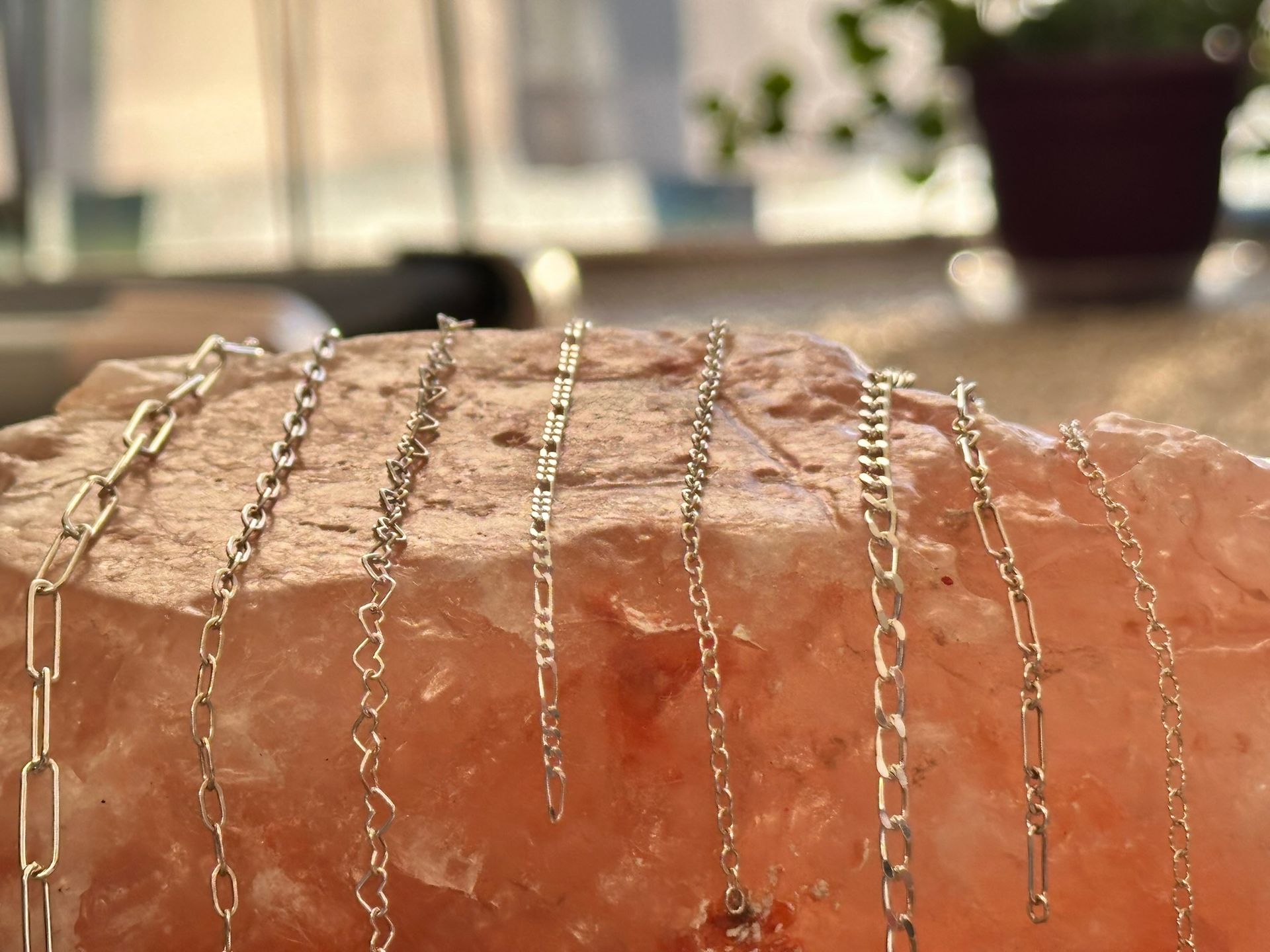 Silver chains displayed on a pink salt block with a blurred background.