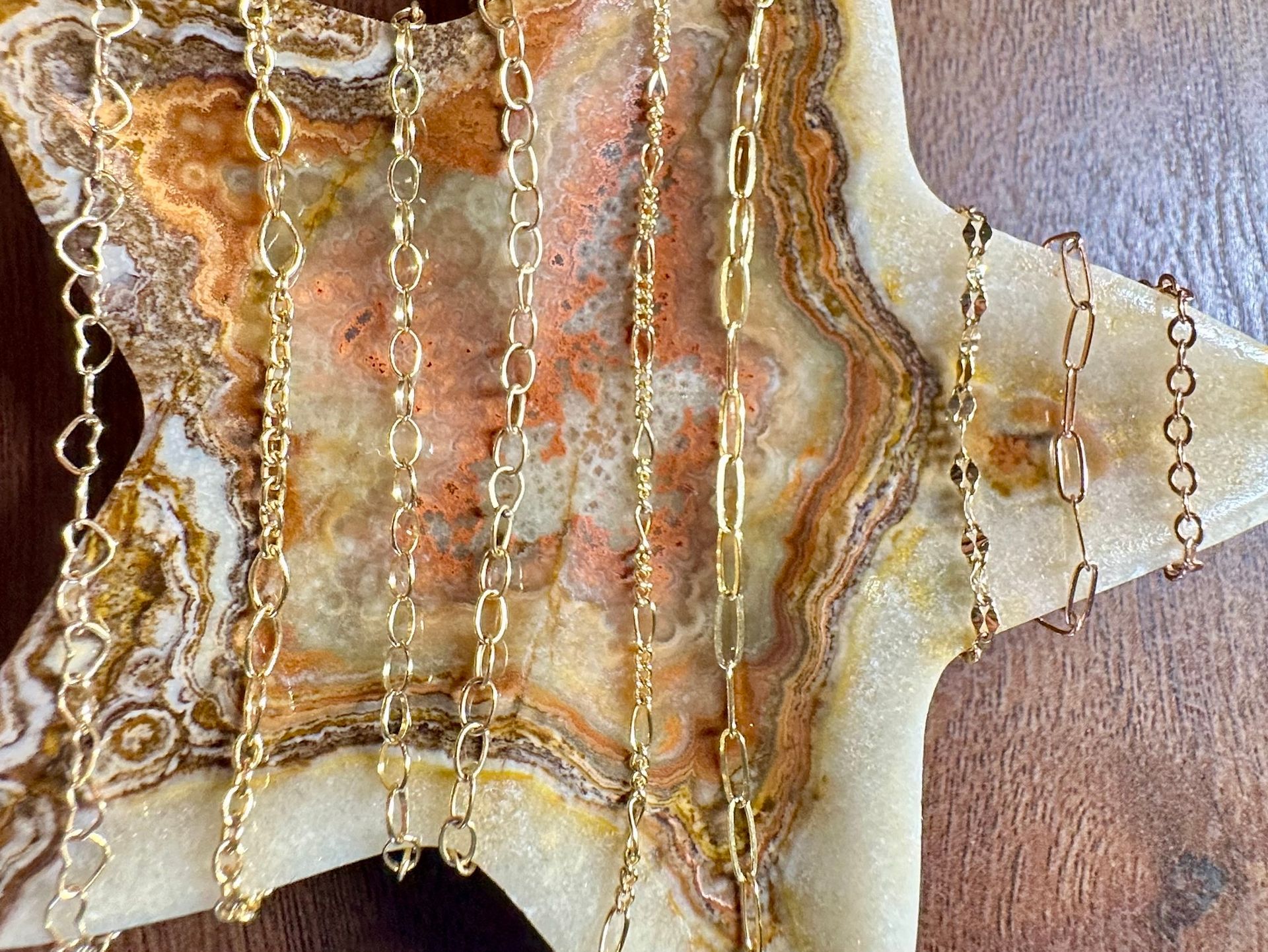 Gold necklaces displayed on a star-shaped, tan and orange stone.