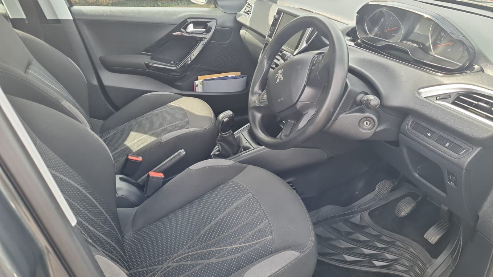 The interior view of a car features dark gray fabric front seats, a steering wheel, and a dashboard with visible gauges.