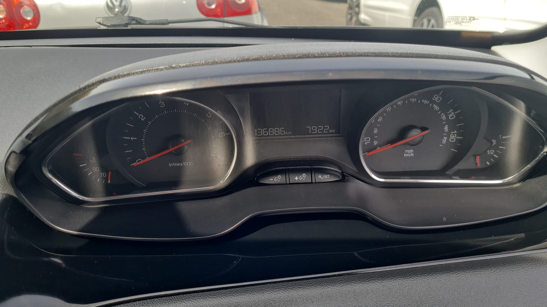 Car dashboard showing a speedometer on the left, a tachometer on the right, and a digital display in the center.