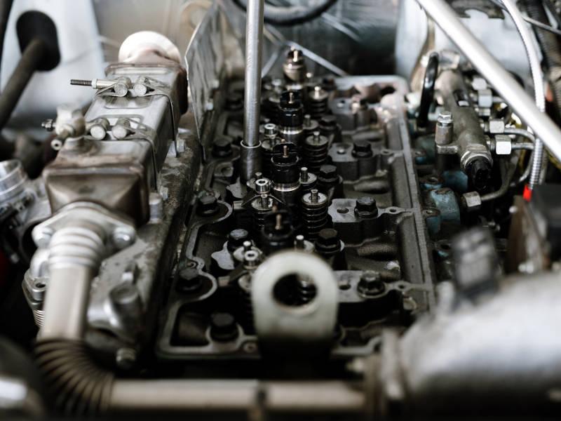 A close-up view of an open car engine block showing valves, springs, and mechanical components during maintenance.