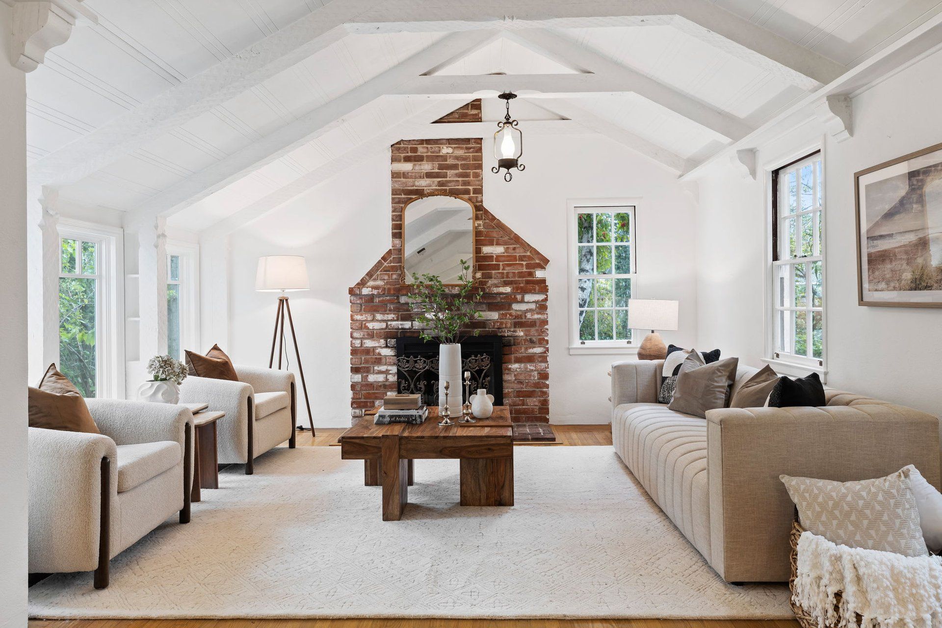 A bright, open-plan dining and kitchen area with light wood ceilings, hardwood floors, a long wooden table, and dark chairs.
